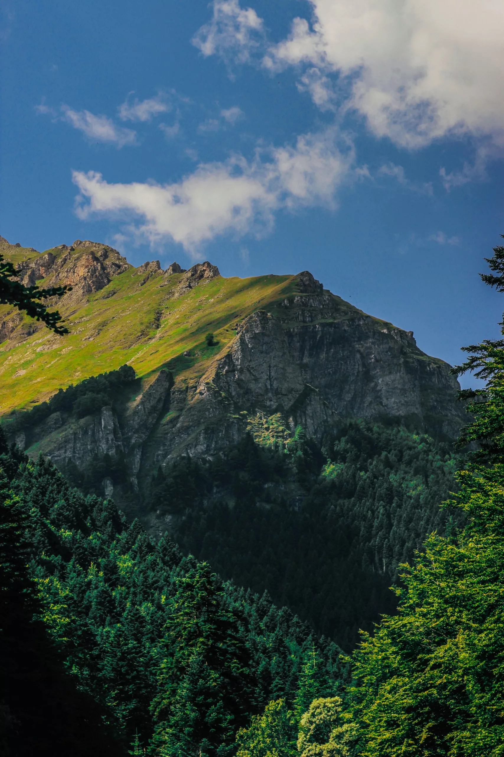 green and gray mountain under white clouds and blue sky